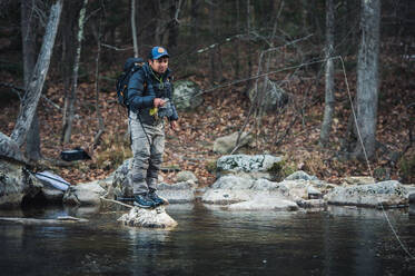 A man fly-fishes during a fall morning on a Maine river - CAVF74318