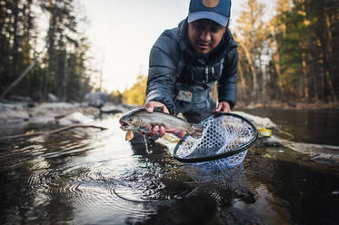 Ein Mann fängt an einem Herbstmorgen in einem Fluss in Maine eine Forelle - CAVF74323