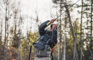 A man sets a hook while fly-fishing in Maine - CAVF74334