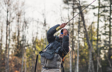 Ein Mann setzt einen Haken beim Fliegenfischen in Maine - CAVF74334
