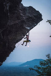 Mann klettert auf einer überhängenden Sportkletterroute in New Hampshire - CAVF74366