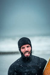 Mann verzieht das Gesicht nach dem Surfen während eines Nordoststurms in Maine - CAVF74370