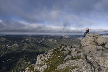 Männer sitzen über den Wolken zwischen den Bergen - CAVF74425