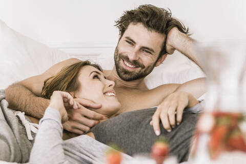 Glückliches junges Paar im Bett liegend, lizenzfreies Stockfoto
