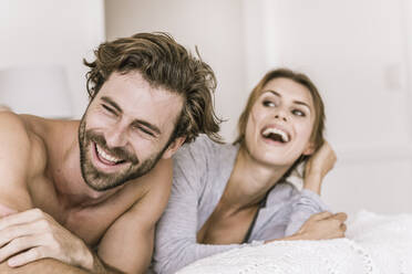 Laughing young couple lying in bed - SDAHF00083