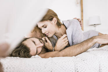 Affectionate young couple lying in bed - SDAHF00086