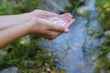 Deutschland, Hände einer jungen Frau, die Wasser aus einem Bach schöpft - LBF02878