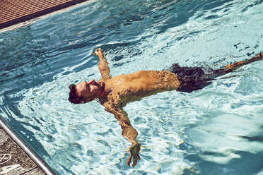 Ein Mann schwimmt auf dem Rücken in einem Pool. - CAVF74530