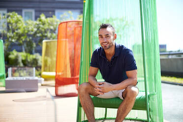 An outdoor portrait of a man in a colorful modern chair. - CAVF74542