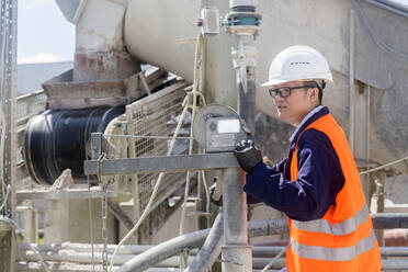 Betonarbeiter bei der Überprüfung einer Maschine in einem Betonwerk - CAVF74609