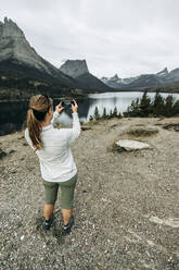 Frau fotografiert mit ihrem Handy die Aussicht auf einen Berg, Montana - CAVF74622