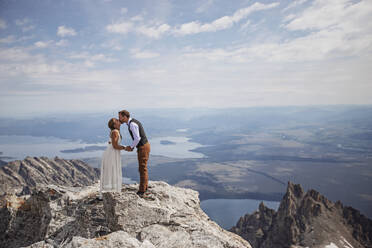 Braut und Bräutigam küssen sich auf dem Gipfel eines Berges in Wyoming - CAVF74645