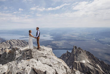 Braut und Bräutigam halten sich an den Händen, nachdem sie auf einem Berggipfel geheiratet haben - CAVF74648