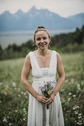 Bride holding wildflower bouquet in a field of flowers, Wyoming - CAVF74654