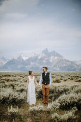 Glücklich lächelnde frisch vermählte Braut und Bräutigam stehen vor dem Grand Teton - CAVF74681