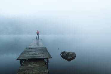 Mann auf Pier im See im Morgennebel - JOHF07684