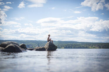 Junge sitzt auf einem Felsen am Meer - JOHF07841