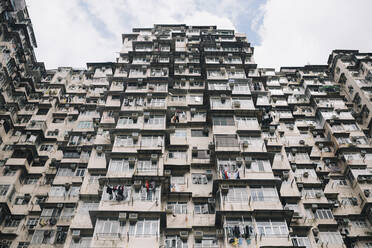 Low angle view of facade of towering residential complex with windows and balconies. - MINF13343