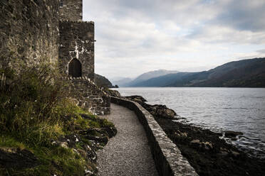 Burg in einer Mauer mit Blick auf einen See und die Berge in der Ferne. - MINF13345