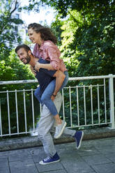 Happy man running and carrying woman piggyback - PNEF02222