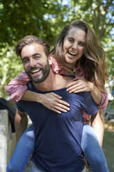 Portait of happy man carrying woman piggyback - PNEF02223