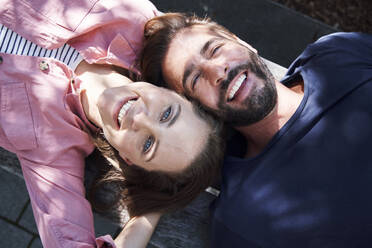 Porträt des glücklichen Paares auf einer Bank liegend, Kopf an Kopf - PNEF02227