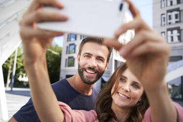 Ein glückliches Paar macht ein Selfie in der Stadt - PNEF02228