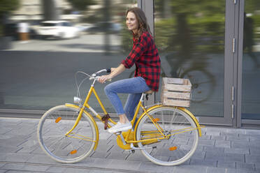 Brunette woman riding bicycle in the city - PNEF02251