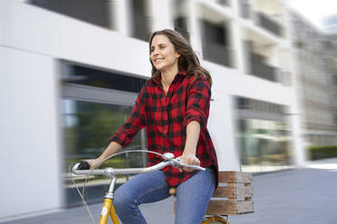 Brunette woman riding bicycle in the city - PNEF02252