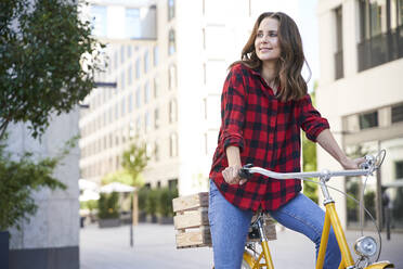 Brunette woman riding bicycle in the city - PNEF02253