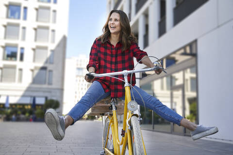 Happy brunette woman riding bicycle in the city stock photo