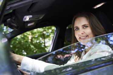 Portrait of smiling woman sitting in car - PNEF02261