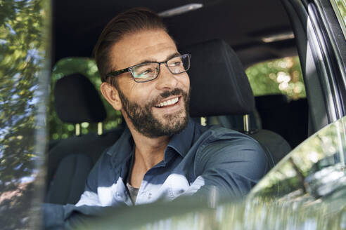 Porträt eines lächelnden Mannes, der im Auto sitzt - PNEF02264