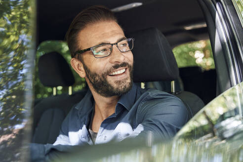 Portrait of smiling man sitting in car - PNEF02264