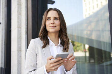 Portrait of confident businesswoman with cell phone in the city - PNEF02265