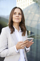 Portrait of confident businesswoman with cell phone in the city - PNEF02266