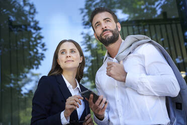 Businessman and businesswoman with cell phone in the city - PNEF02290