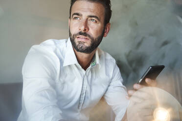 Portrait of businessman wearing white shirt holding cell phone - PNEF02299