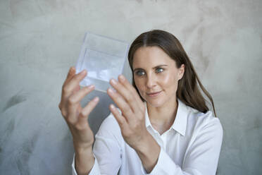Porträt einer selbstbewussten Frau mit Blick auf einen transparenten Würfel - PNEF02307