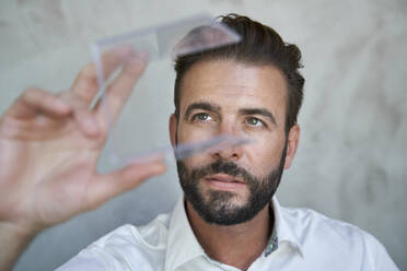 Porträt eines Geschäftsmannes mit Blick auf einen transparenten Würfel - PNEF02310