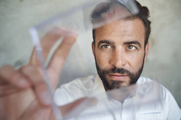 Porträt eines Geschäftsmannes mit Blick auf einen transparenten Würfel - PNEF02311