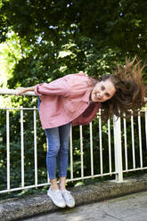 Portrait of happy brunette woman holding railing outdoors - PNEF02320