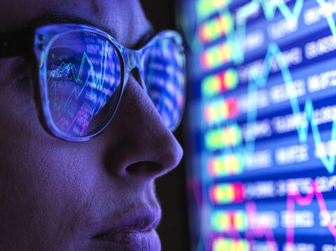 Weibliche Analystin betrachtet Finanzmarktdaten auf einem Bildschirm, lizenzfreies Stockfoto