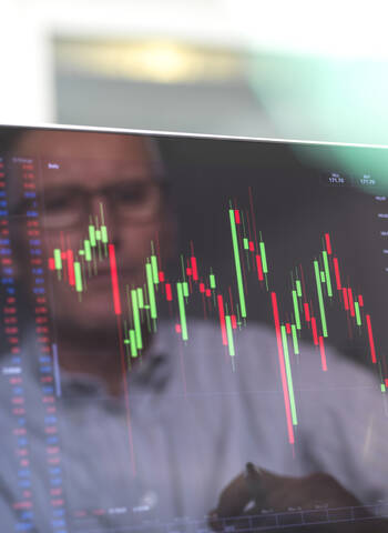 Reflexion eines Aktienhändlers, der die Entwicklung des Aktienkurses eines Unternehmens auf dem Bildschirm betrachtet, lizenzfreies Stockfoto
