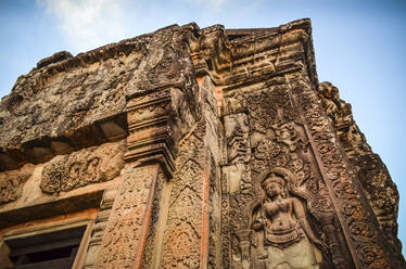 Ankor Wat, ein historischer Khmer-Tempel aus dem 12. Jahrhundert, der zum UNESCO-Weltkulturerbe gehört, mit Bögen und geschnitzten Steinen, die sich mit großen Wurzeln über das Mauerwerk erstrecken. - MINF13394