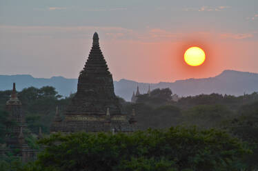 Sonnenuntergang über fernen Bergen mit Stupa des Tempels im Vordergrund, Bagan, Myanmar. - MINF13426