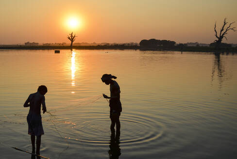 Zwei Jungen angeln bei Sonnenuntergang in einem See, Amapura, Myanmar. - MINF13433