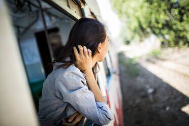 Young woman riding on a train, looking out of window. - MINF13440