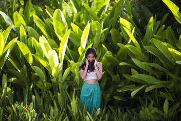 Young woman standing in rain forest with lush green foliage. - MINF13458