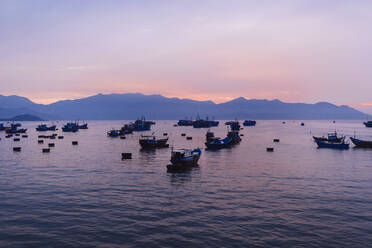 Große Gruppe von Fischern in traditionellen Fischerbooten auf dem See bei Sonnenaufgang, Berge in der Ferne. - MINF13476